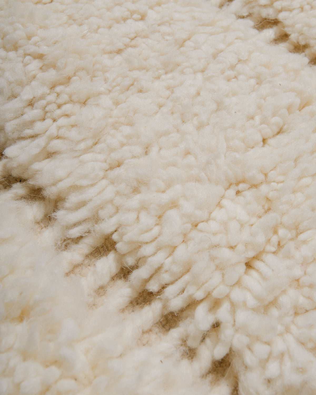 Texture of rug made of knotted and flat woven cream wool, giving it a textured surface.